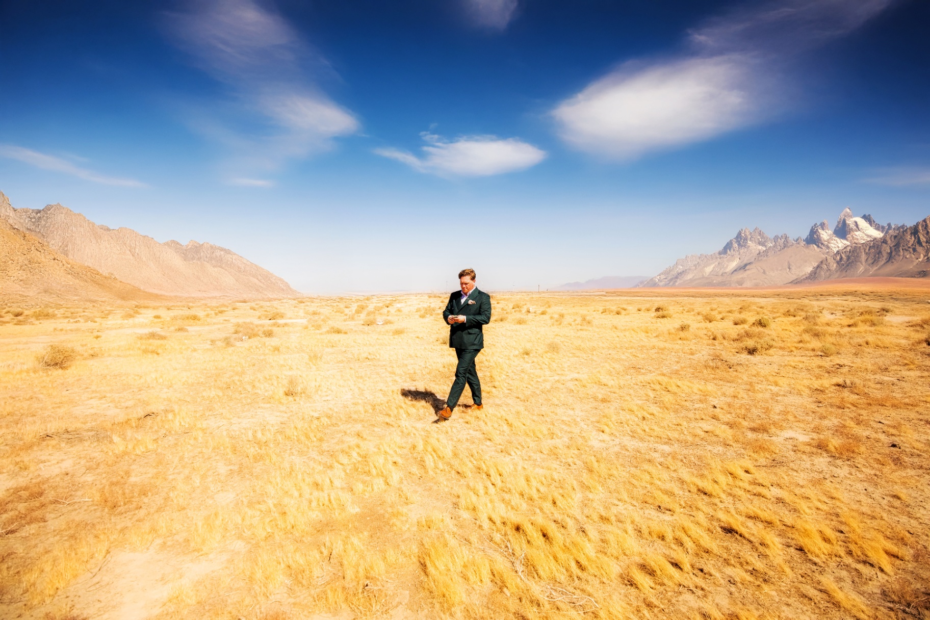 Scott Syme, luxury magician and entertainer for private events in Los Angeles, walking through a desert landscape in a tailored suit